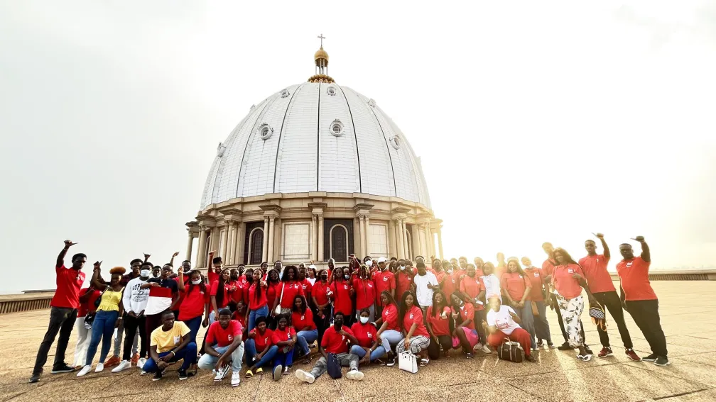 Groupe de personnes en rouge devant un grand b&acirc;timent en forme de d&ocirc;me.