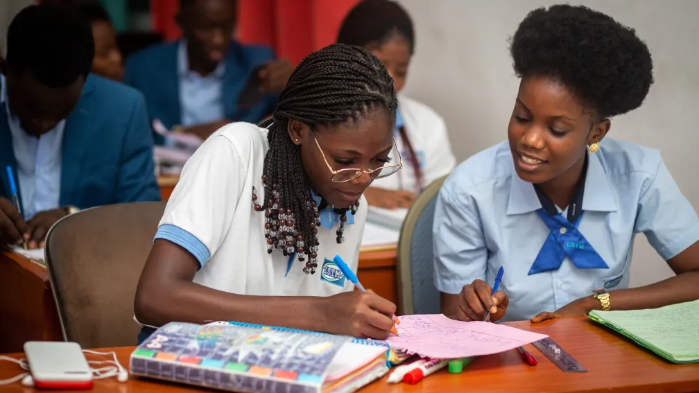 &Eacute;tudiantes en uniforme travaillant ensemble &agrave; un bureau.
