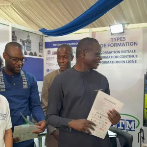 Des personnes discutant &agrave; une exposition, tenant des brochures.