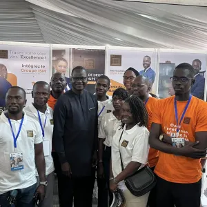 Groupe de personnes souriantes &agrave; une exposition, certains portent des t-shirts orange.